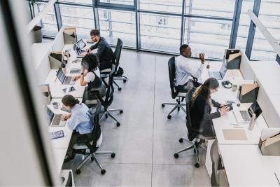 Werken met MS - topdown foto van een kantooromgeving waar vijf mensen achter hun bureau aan het werk zijn