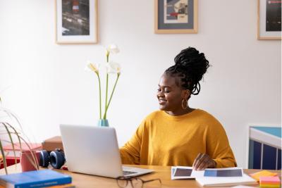 Persoon die thuis aan het werk is, met laptop, accessoires en documenten op haar bureau