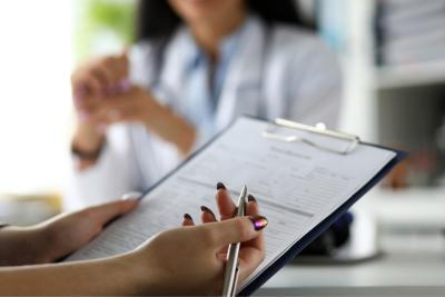 VAPH tegemoetkomingen - persoon die een formulier invult met een arts op de achtergrond